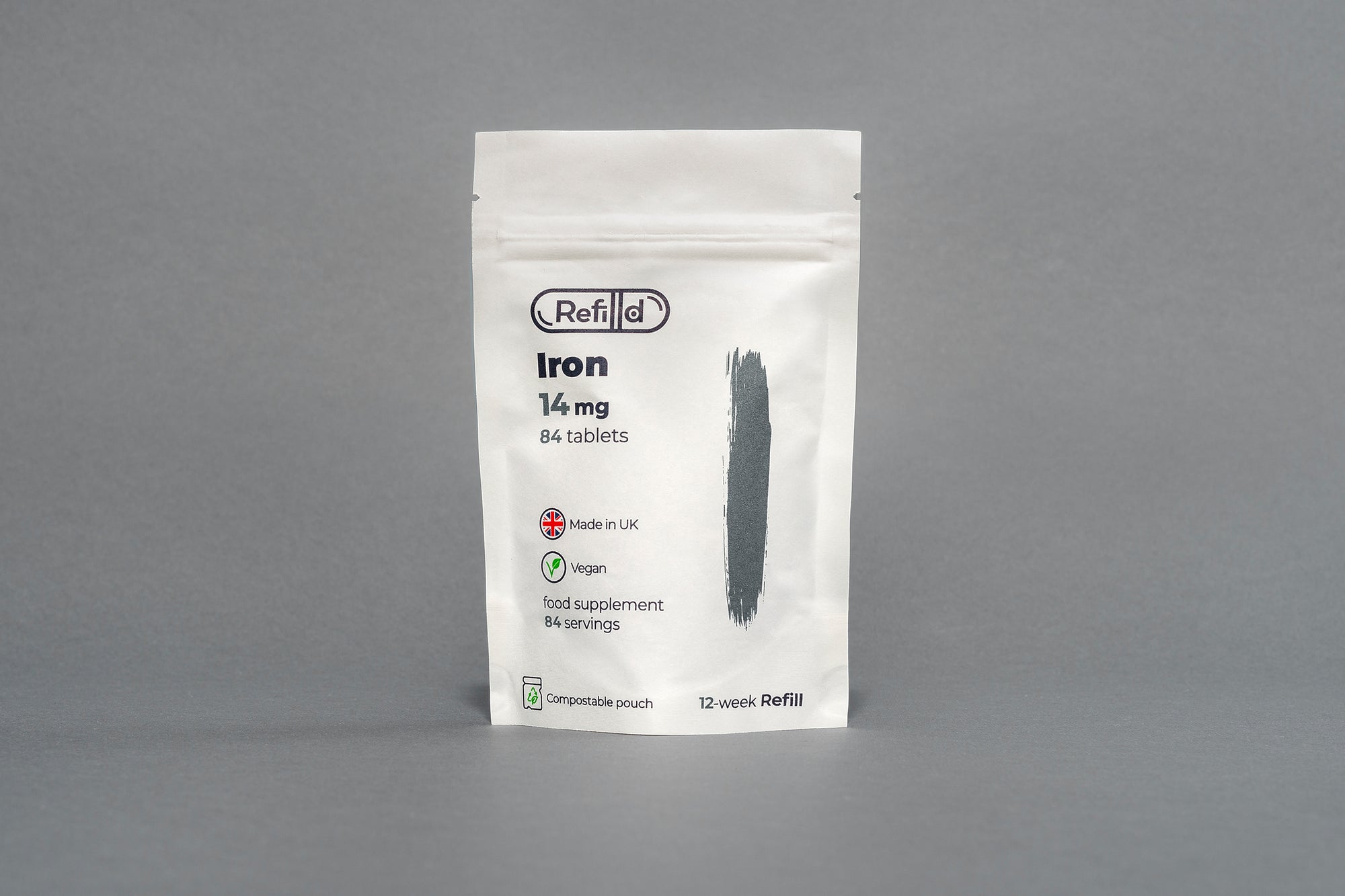 Refilld Iron 14 mg compostable refill pouch displayed on a gray background. Iron supplement, 14 mg, compostable packaging, eco-friendly.