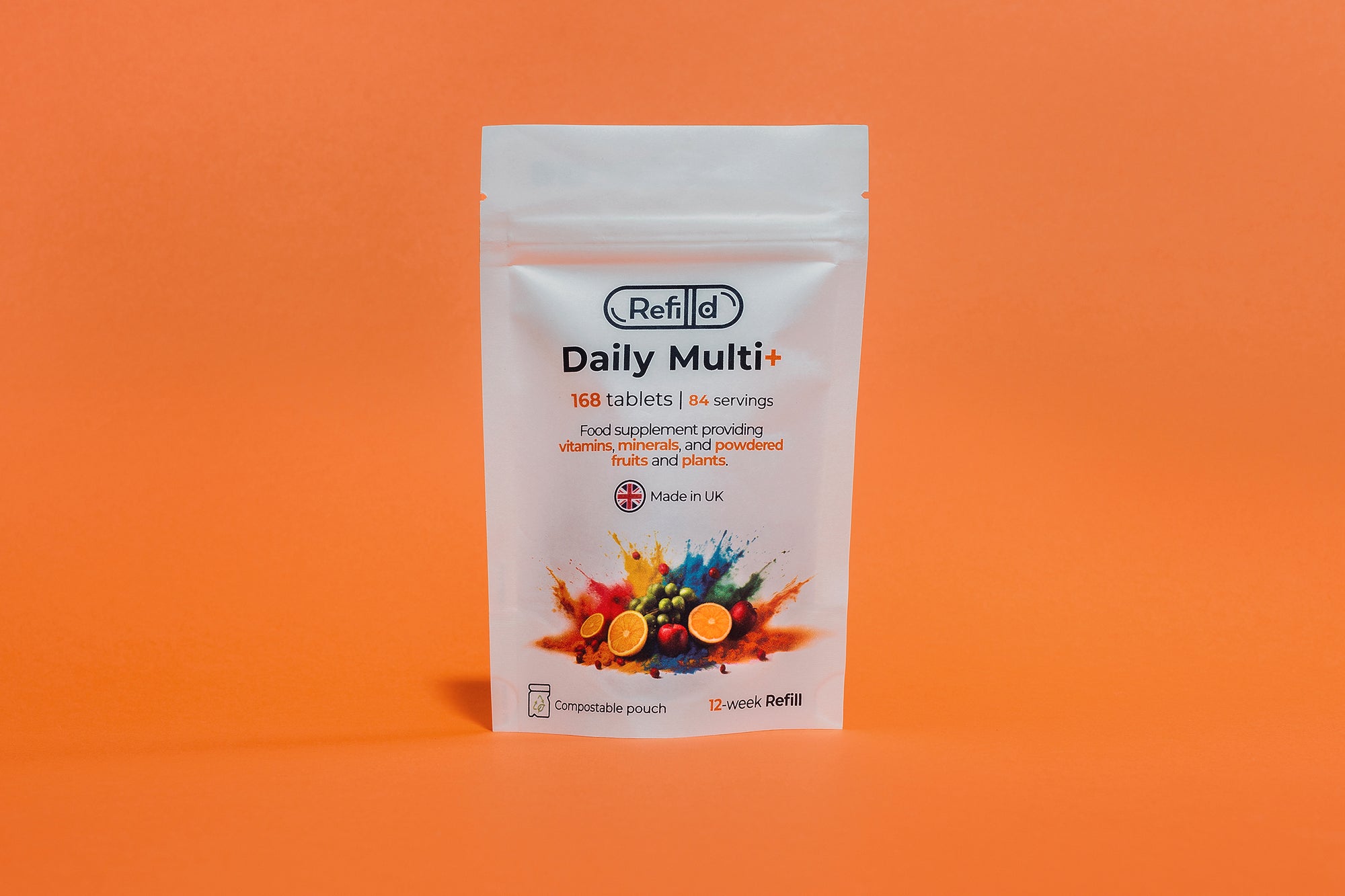 Refilld Daily Multi+ compostable refill pouch for a 12-week supply, displayed on an orange background. Refilld Daily Multi+, compostable refill pouch, 12-week supply, eco-friendly packaging, orange background