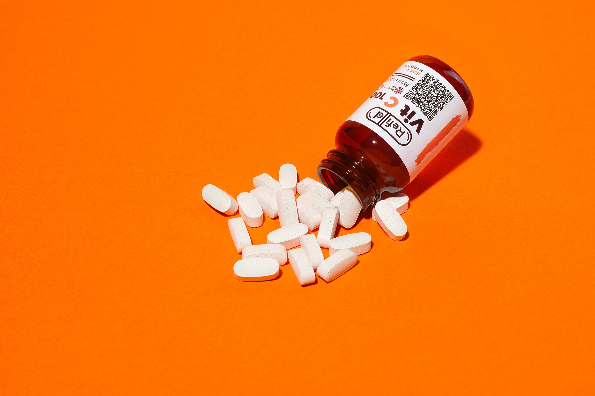 Spilled Refilld Vit C 1000 mg bottle with white tablets on an orange background.
Refilld Vit C 1000 mg, spilled bottle, white tablets, vitamin C, orange background, immunity support