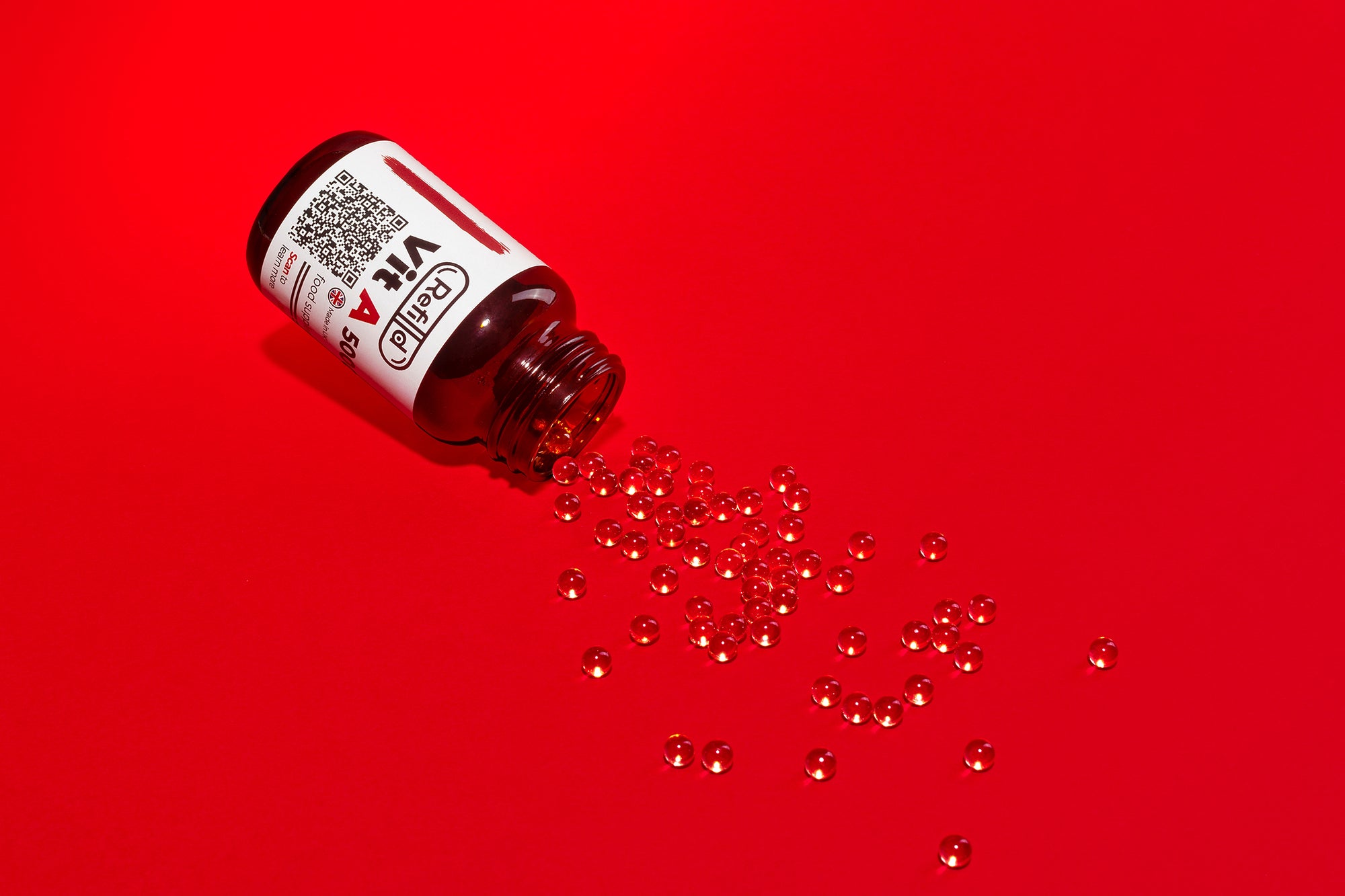 Spilled Refilld Vit A 5000 iu bottle with soft-shell capsules on a red background.
Refilld Vit A, 5000 iu, spilled bottle, vitamin A supplement, soft-shell capsules, red background