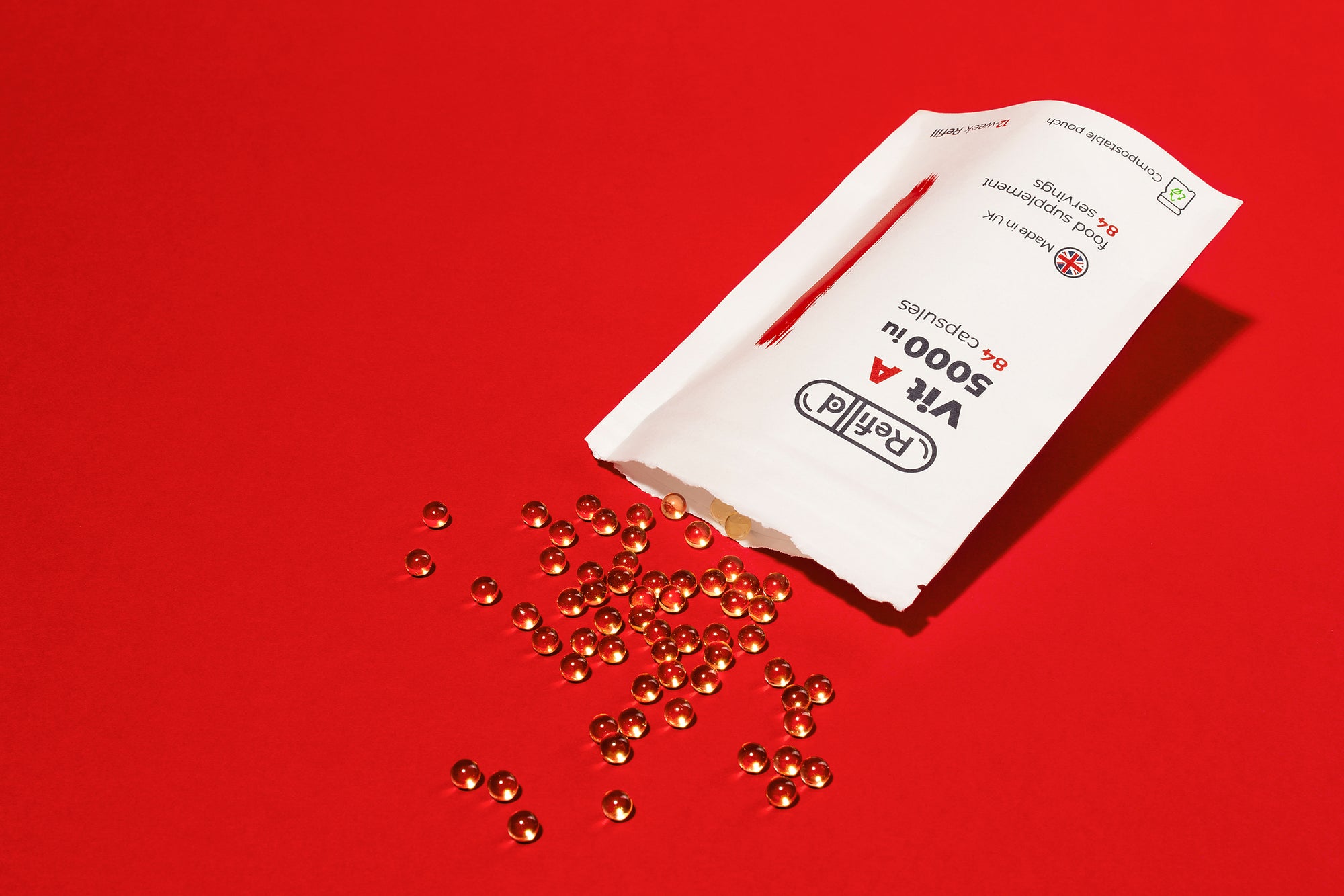 Refilld Vit A 5000 iu compostable refill pouch with soft-shell capsules spilling out on a red background.
Refilld Vit A, 5000 iu, compostable refill pouch, eco-friendly, soft-shell capsules, red background