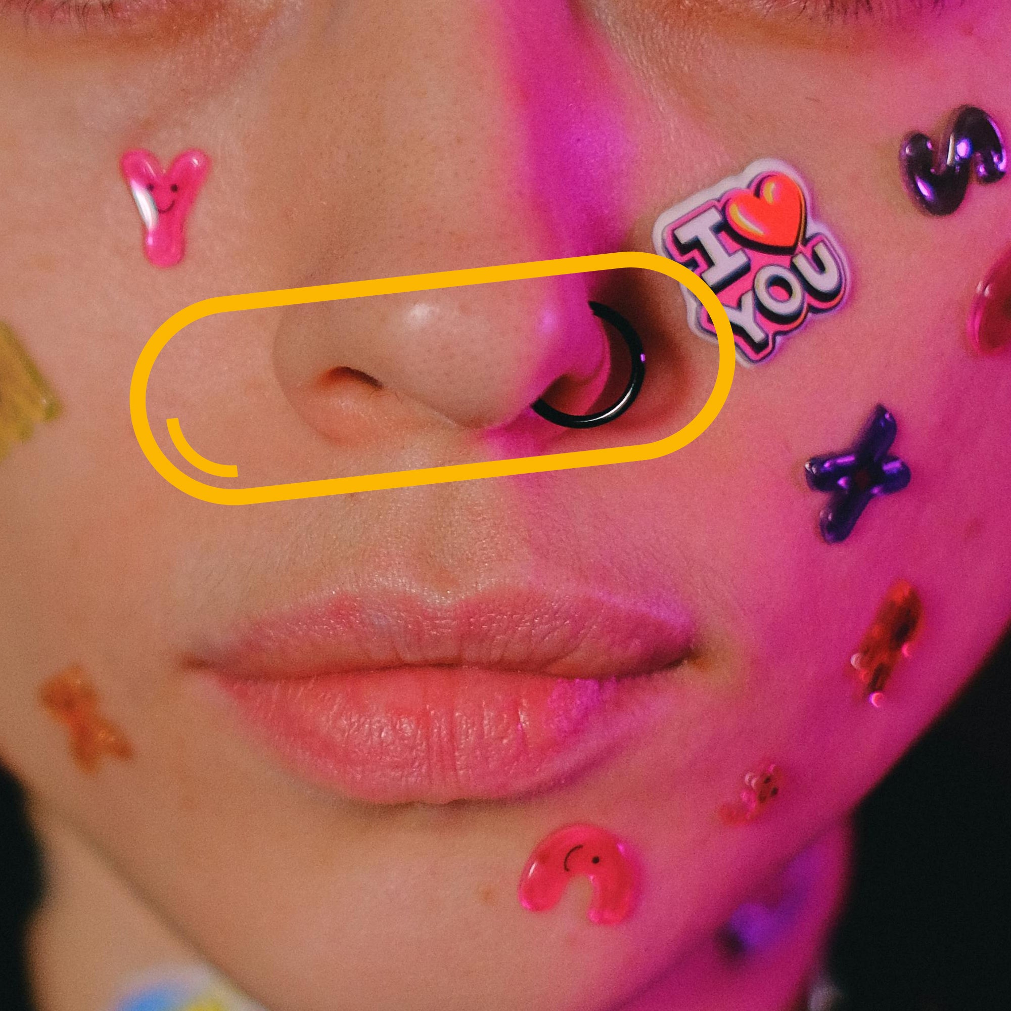 A creative close-up of a person’s face decorated with vibrant stickers and a black nose ring, symbolising the playful and unique character of Vitamin D3 benefits.